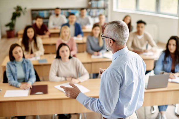 A mature teacher teaching students in a class room and proving "Education is Important."